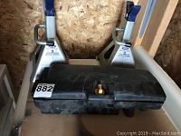 Two silver 3-ton jack stands with blue tops and a black plastic case on the shelf.