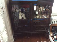 Full front view of vintage wooden display cabinet with two glass doors and wood decorative design.