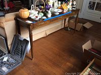Full view of the wooden sofa table showing its size, turned legs, drawer, and wood grain finish. Items on table not included.