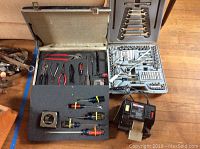 Photo of pliers, screwdrivers, tape measures, and Craftsman wet sharp machine on the floor and in foam trays