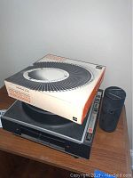 Side and top view of GAF Anscorama projector with boxed GAF Amscorama slide tray and lens cover on table