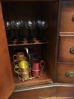 12 green stem wine glasses on shelf, aluminum mugs in carrier below