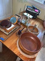 Wide shot showing multiple wooden bowls and platters, mantle clock, decor items, vintage radio, and nut cracking dish on table.