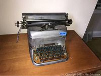 Full side view showing overall shape and condition of Smith Corona typewriter on wooden surface.