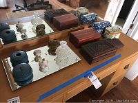 Photo showing hand carved cedar boxes, vanity mirror, perfume bottle, and decorative tins arranged on a dresser with mirror