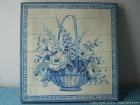 Front view of square oilcloth painting with blue floral basket and border.