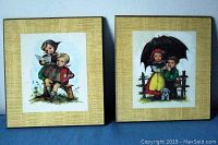 Front view of two framed Hummel plaques showing children in vintage clothing, one with accordion and the other with umbrella and dog