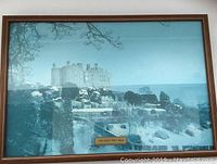 Framed photographic print showing Powis Castle and surrounding gardens under a blue sky, labeled with a plaque.