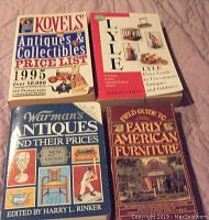 Four antique price guide books laid out on fabric, titles visible including Kovels, Lyle, Warman's, and Early American Furniture guides.