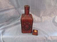 Brown leather-covered whiskey bottle with embossed lion crest, shown with small square box