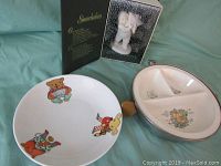 Photo showing the front view of the white baby dish with colorful animal illustrations, the vintage divided dish with metal holder, and the boxed Snowbaby figurine in background.