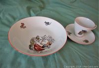 Three-piece China baby dish set pieces shown with cartoon artwork on white porcelain with red rim detail.