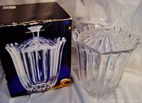 Photo of Studio Nova candy jar with lid next to its original box, showing clear crystal with vertical fluted sides and scalloped rim.