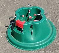 Green plastic Christmas tree stand with clover-shaped collar and red securing screws on a wide base