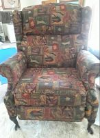 Front view of a recliner armchair with a colorful, patchwork-patterned fabric upholstery and wooden legs