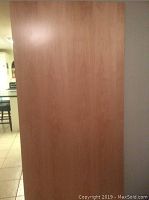 Front side of a single large solid wood door with smooth natural wood finish.