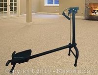 Black folding manual exercise bench with pull straps shown set up on carpeted floor.