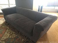 Front-side view of large grey sofa sectional piece on area rug in living room