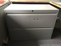 Front and side view of the 2 drawer lateral file cabinet showing the exterior, locking mechanism, and scratches on top drawer.