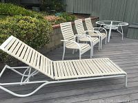 View showing one white patio lounge chair at reclined position on decking with greenery in background