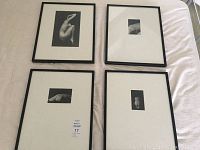 Four framed black and white nude photographs laid out on a flat surface, viewed from the top down showing all frames together.