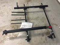 Black Yakima Viper 2 bike roof rack laid out on floor showing frame and support arms with attached manual.