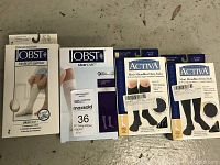 Four pairs of compression socks boxes including two Jobst UlcerCARE and two Activa Men's Microfiber Dress Socks with labels and packaging visible.