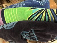 Photo showing close-up neckline of multiple stacked beach towels with colorful patterns and textiles.