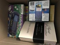 Photo of multiple board games including Saltek Craps Professor electronic craps game, a Warning Strip Poker Kit deck, and more.