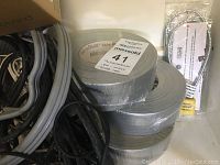 Several rolls of silver duct tape with assorted wires and two packaged padlocks