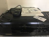 Front view of the Sony DVD/CD player with remote control placed on top, showing model labels.