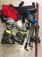 Photo showing the full ski lot with boots, vest, helmet, gloves, poles, and skis on the floor.