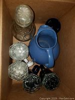 Top view of the blue ceramic pitcher, decanter with stopper, and 5 mugs.