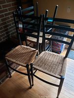 Four wood cane seat chairs stacked together showing ladder back design and woven cane seats