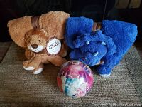 Two unopened kids animal and blanket sets (brown lion and blue triceratops) and a colorful ball on floor.