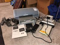 HP Deskjet 5150 printer, power adapter, manual, Kodak EasyShare camera on printer dock, and cables arranged on carpeted floor.