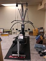 Full view of Bowflex home gym exercise machine including upper pulleys and resistance rods on mat with Bowflex branding.