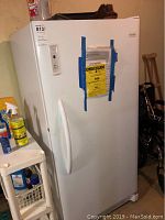 Frigidaire freezer front view with door handle and Energy Guide label taped on door.
