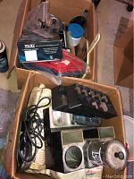 Boxes containing Wahl Super Taper clippers in packaging, clipper blades, comb jars, brushes, smocks, and black tabletop organizers for clippers.