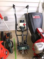 Front view of Bolens tiller, showing black frame, white fuel tank with red cap, and handles.