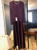 Formal two-piece dress set hanging in front of mirror, showing full length satin skirt and sequined jacket.