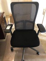 Front view of Haworth black mesh office chair with label on armrest