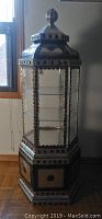 Full view of the tin pressed vetrine cabinet with all glass sides and decorative metal top.