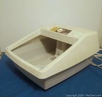 Oblique side view of beige plastic foot massager showing overall shape and slanted foot well.