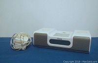 Front view of the white iHome iPod dock station with gray speaker grills and power supply cord coiled beside it.