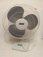 Front view of the Super table top fan with three black blades behind protective metal grille and control buttons on the base.
