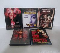Photo of five horror DVD cases arranged on a flat surface. Titles include Body Snatchers, The Silence of the Lambs, Creepshow, Stigmata, and House of 1000 Corpses.