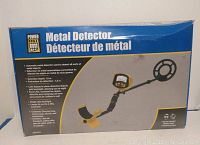 Box front showing Power Fist Metal Detector label with product details including detection depth 1.5m and features such as LCD display and LED flashlight.