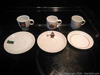Espresso cups and saucers laid out individually showing variety in logos and styles.