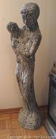 Side view of the plaster cast statue showing detailed sculpting of the lady holding a child